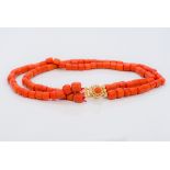 A two strand coral bead necklace Set with a coral cabochon mounted pierced gold clasp. 39.