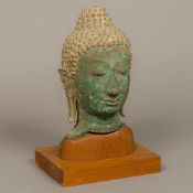 An antique bronze bust of Buddha Typically modelled wearing a headdress and with extended earlobes,