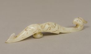 A Chinese celadon jade belt hook Of typical form, carved with a phoenix mask. 16 cm long.