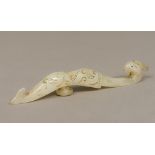 A Chinese celadon jade belt hook Of typical form, carved with a phoenix mask. 16 cm long.