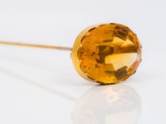 A citrine set hatpin The large facet cut stone set in an unmarked gold mount. 17.5 cm long.