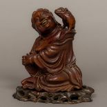 A Chinese carved wood group Worked as a jovial seated figure with a piglet on his shoulder,