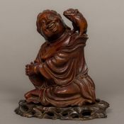 A Chinese carved wood group Worked as a jovial seated figure with a piglet on his shoulder,