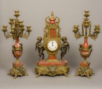 A gilt metal mounted red marble triple clock garniture The centrepiece flanked with the garnitures