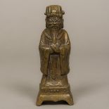 A Chinese bronze figure of an attendant Modelled hands crossed and wearing a headdress.