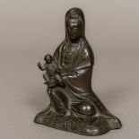 A late 17th/early 18th century Chinese bronze figure of Guanyin Modelled seated with an infant on