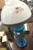 A Victorian blue glass oil lamp with enamel painted decoration and with painted opaline shade