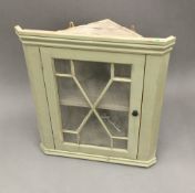 A small painted pine hanging glazed corner cabinet