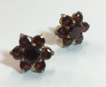 A pair of 9 ct gold garnet set flower head earrings,