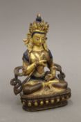 A Tibetan gilt copper Buddha with painted face and hair,