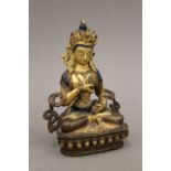 A Tibetan gilt copper Buddha with painted face and hair,