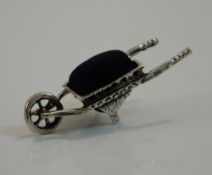 A silver pin cushion in the form of a wheelbarrow