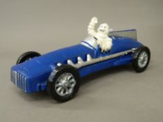 A cast iron model of the Michelin man driving a car