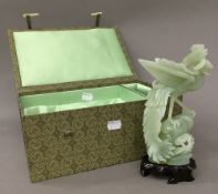 A pale green jade bird, with wooden stand,