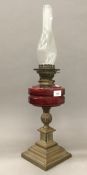 A Victorian brass oil lamp with ruby glass reservoir