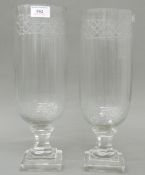 A pair of small glass hurricane lamps