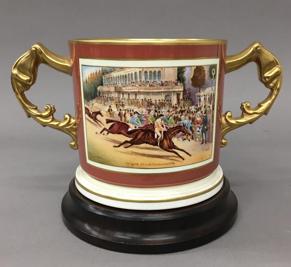 An Aynsley porcelain Glorious Goodwood twin handled cup on stand