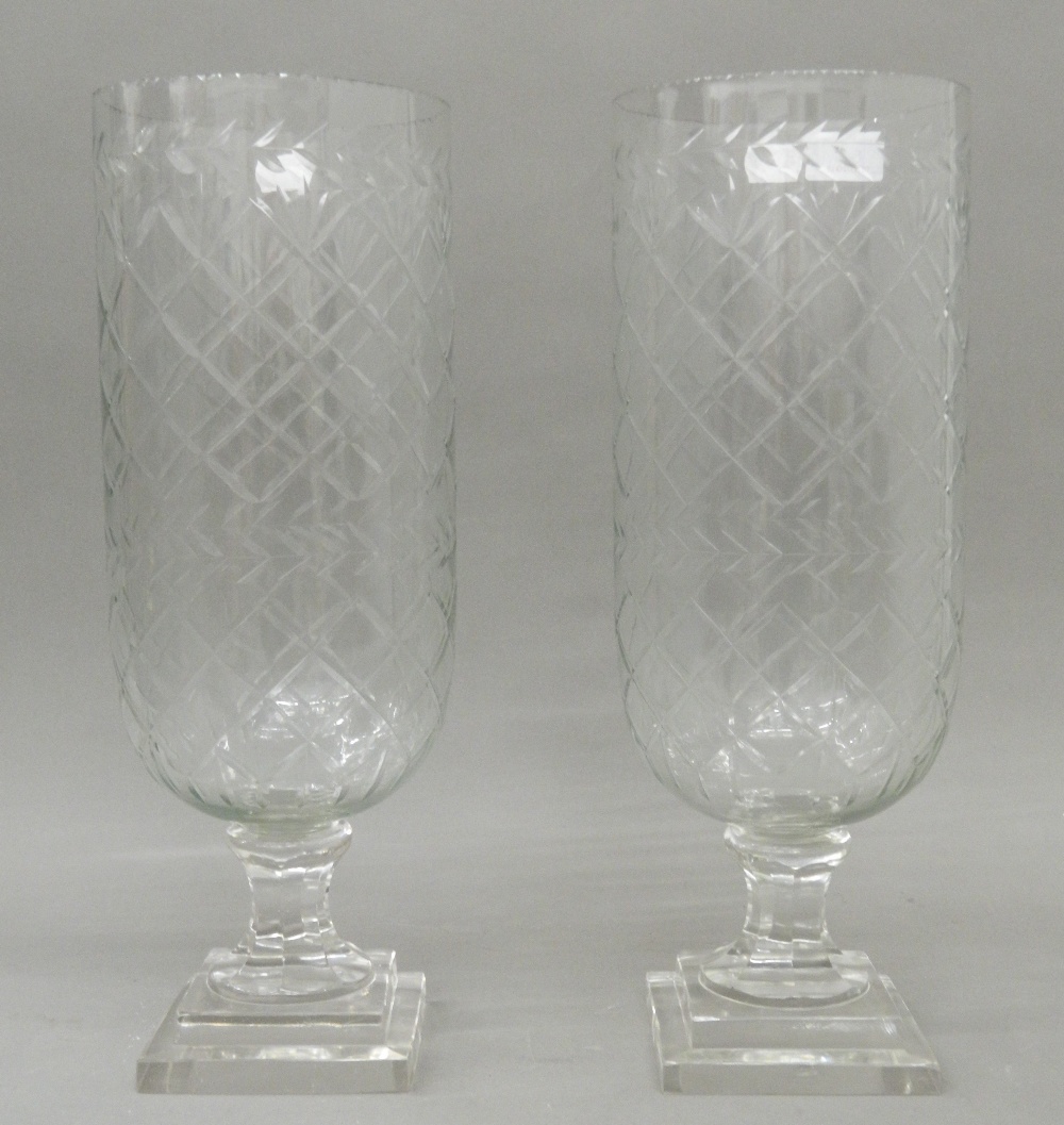 A pair of large glass hurricane lamps