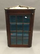 A George III mahogany glazed hanging corner cabinet