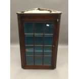 A George III mahogany glazed hanging corner cabinet