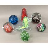 Six decorative glass paperweights and a green glass lion