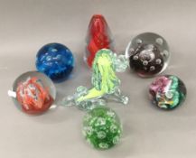 Six decorative glass paperweights and a green glass lion