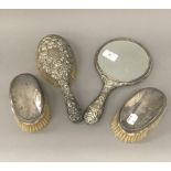 Three silver backed brushes and a silver backed mirror
