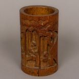 A Chinese bamboo brush pot Carved with scholarly figures amongst trees. 16.5 cm high.