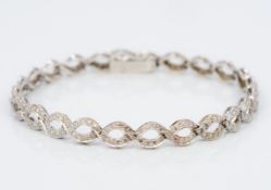 A 9 ct white gold diamond set bracelet Of scrolling link form. 18 cm long.