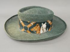 A green hessian type wide brimmed hat The head band with images of horse.