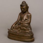 A patinated bronze figure of Buddha Typically modelled seated in the lotus position,