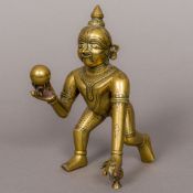 A 19th century Indian brass figure of Krishna Typically modelled holding a ball in his right hand.
