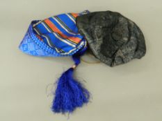 Two blue smoking caps One with covered button the other with a blue tassel and a label to the