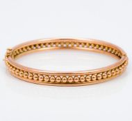 A 9 ct gold bangle form bracelet With central ball decoration. 6.5 cm wide.