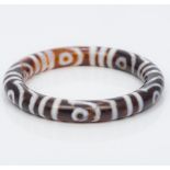 A Tibetan agate bangle Of typical form, with banded decoration. 8 cm diameter.