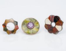 Three Scottish specimen stone mounted silver brooches One centrally set with a facet cut amethyst.