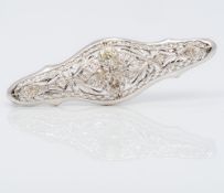 A 14K white gold diamond set brooch Of pierced navette form,