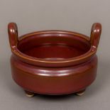 A Chinese red ground porcelain censer Of squat circular form, with twin loop handles,