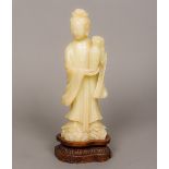 A Chinese carved soapstone figure of Guanyin Typically modelled holding a vase,