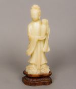 A Chinese carved soapstone figure of Guanyin Typically modelled holding a vase,