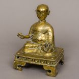 An 18th century Tibetan bronze Buddha Modelled seated in the lotus position holding a small cup and