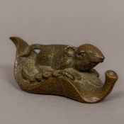 A patinated bronze model of a rat Modelled perched on a leaf between coins, the underside signed.