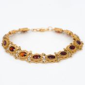 A 9 ct gold garnet set bracelet Each stone of oval faceted form. 17.5 cm long.