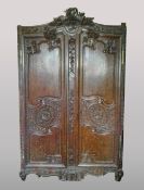 A 19th century French carved oak armoire The curved top rail centred with a wheatsheaf and fruiting