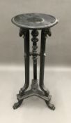 A 19th century ebonised torchere stand The dished circular top above the three rams mask headed