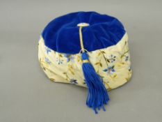 A cream silk embroidered and blue velvet smoking cap With covered button and blue tassel,