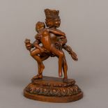 A carved wooden figure of a three headed four-armed deity Modelled engaging in a sexual act with a