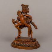 A carved wooden figure of a three headed four-armed deity Modelled engaging in a sexual act with a