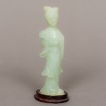A Chinese light green hardstone carving Modelled as a female attendant holding a fan,