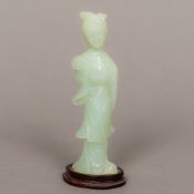 A Chinese light green hardstone carving Modelled as a female attendant holding a fan,